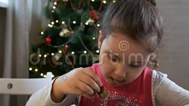 圣诞前夜坐在圣诞树旁吃巧克力圣诞老人的女孩。 在家庆祝圣诞节